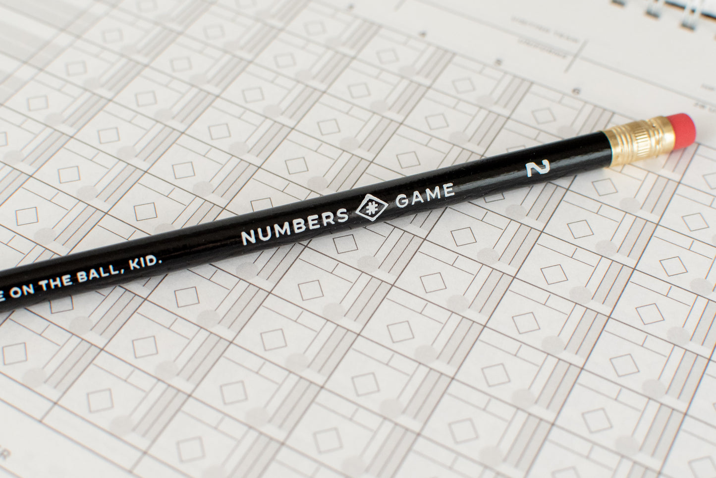 A black Numbers Game pencil resting on a blank scoresheet